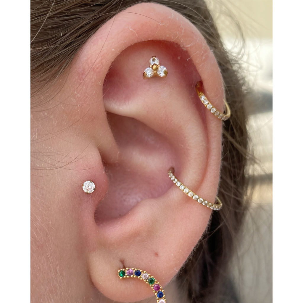 orelha com projeto auricular de piercings em titânio dourado (piercing flat, piercing helix, piercing conch, piercing tragus e furo de brinco)